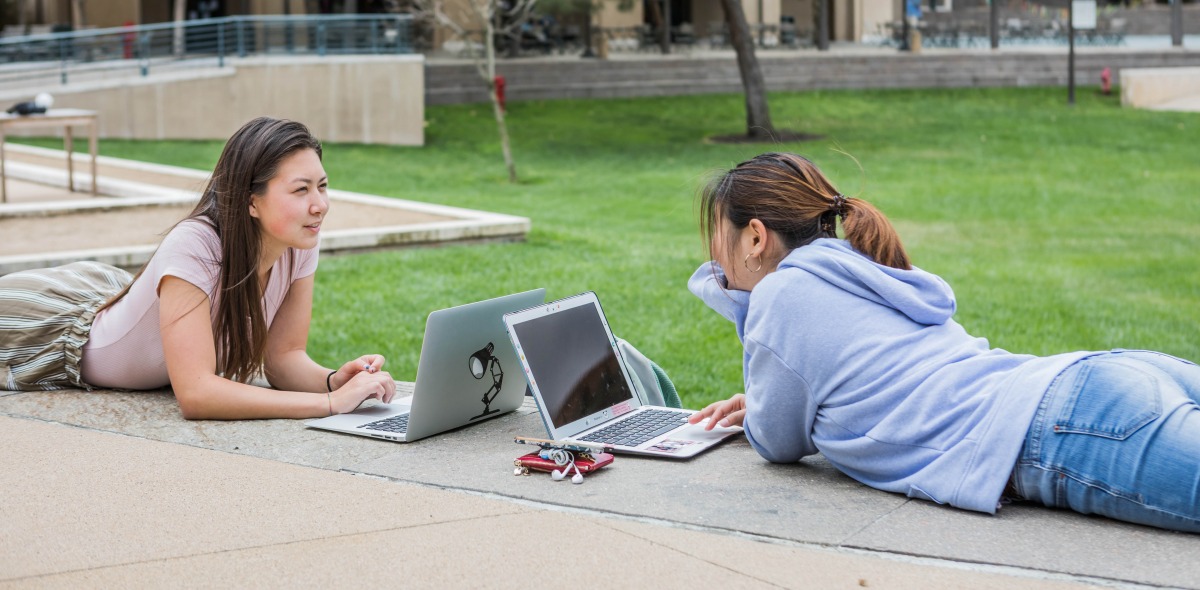 Image of students working outside on laptops.