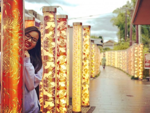 Student smiling from behind light totems in Japan