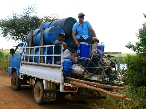 A picture of Michael Schaefer on a truck bed with multiple water barrels. 
