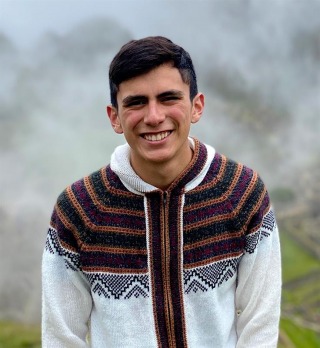 Student in multicolor sweater smiling at camera