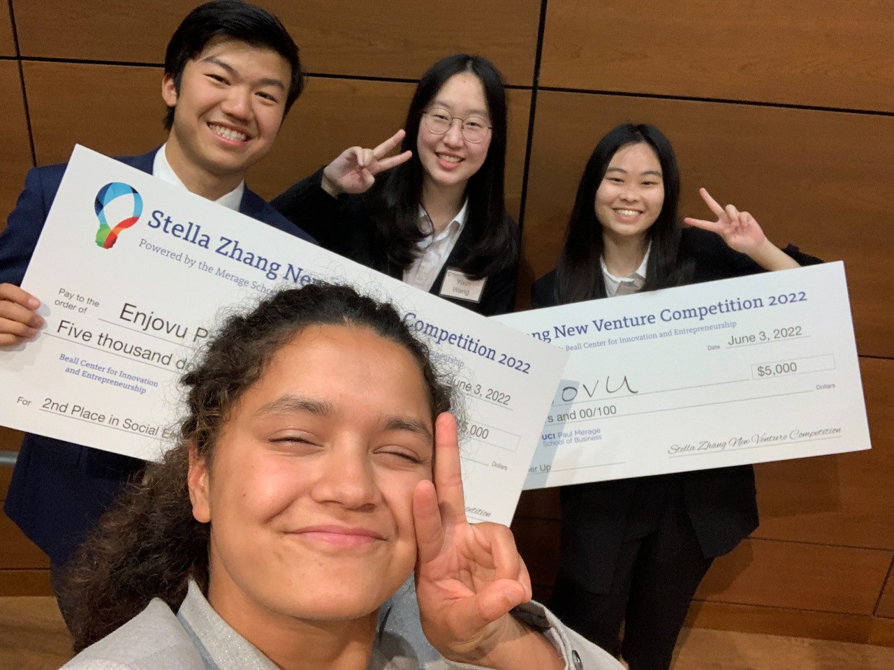 Students pose with giant checks at the UCI New Venture Competition