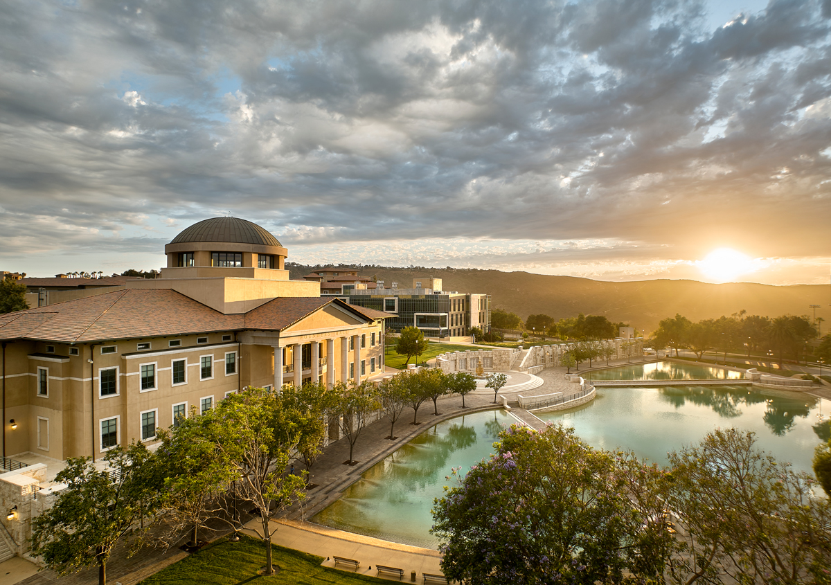 Aerial view of Founders Hall and Peace Lake with clouds and the sun on the horizon