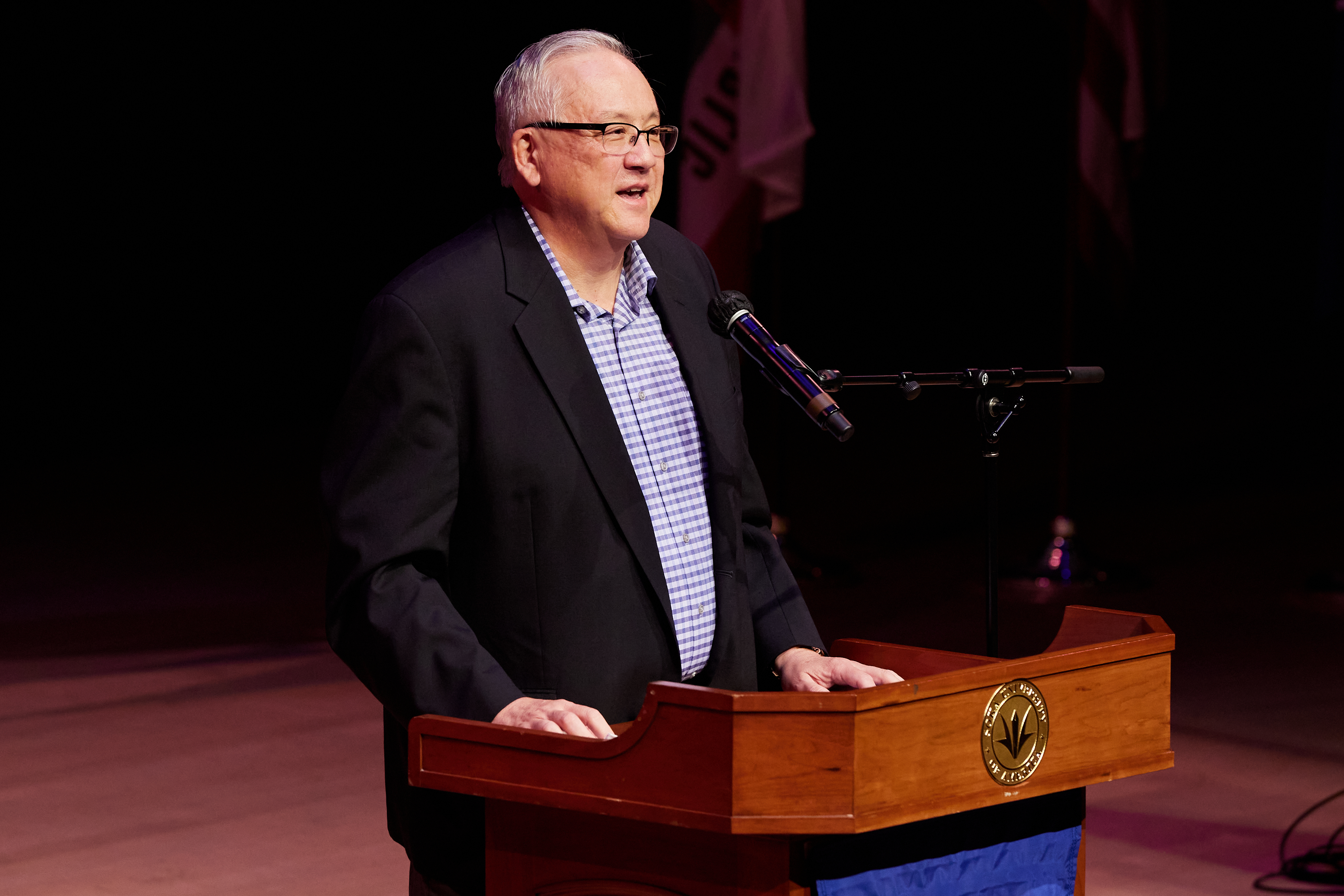 President Ed Feasel smiles as he stands at the podium and addresses the Class of 2026.