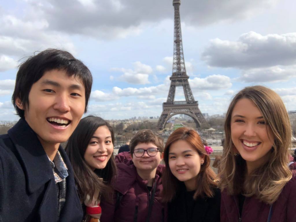 A group of 5 male and female students stand in front of the Eiffel Tower during a study abroad trip.
