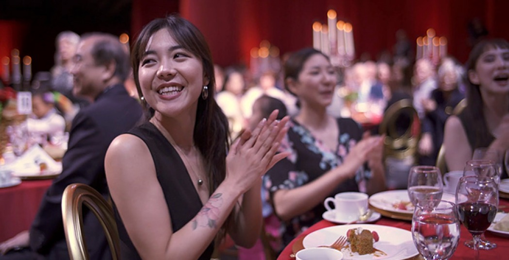 Woman smiles and applauds while sitting at banquet table