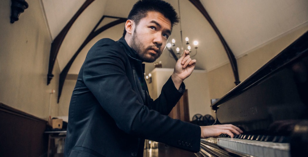 Man in black suit playing the piano