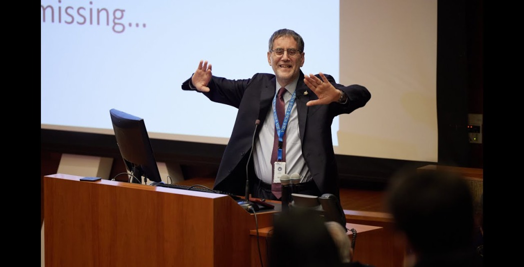Andrea Bartoli gestures with both arms during his presentation about conflict resolution
