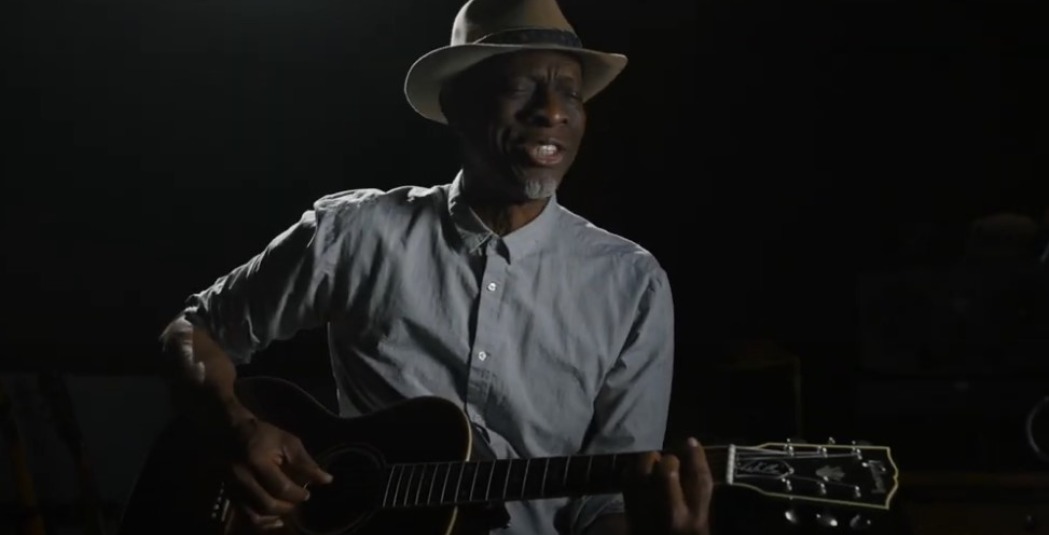 Man playing a guitar against a dark background