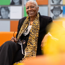 Gail E. Thomas wears a tiger-striped scarf and a black suit as she smiles at the camera
