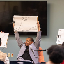 Event speakers are holding up large papers