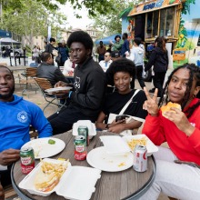 A group of people sitting and eating pose for a photo during the 2025 Homecoming event