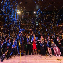 The Class of 2024 celebrates as confetti and streamers fall on them in the Performing Arts Center during commencement.