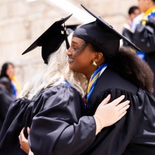 Two graduates hug after commencement.