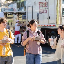 Three students wearing backpacks, carry their In-N-Out Burger meals