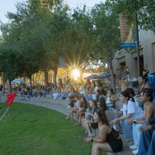 A group of students sit along the Campus Green and watch the activities unfold during the Welcome Back event.
