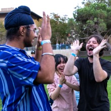 Students smile and high five after winning a competition during the welcome back event