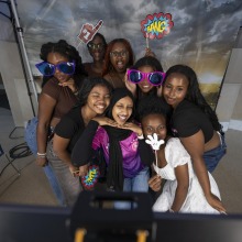 A group of female students pose with various props and signs in the SUA photobooth during the Welcome Back event.