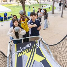 Shot from the angle of the basketball hoop, a group of four students play pop-a-shot