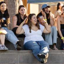 Six women sit and react as they watch the welcome back festivities.