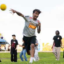 Action shot of a male student throwing a yellow dodgeball with his teammates standing in the background.