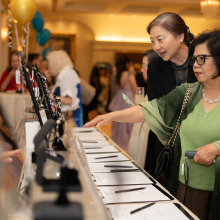 Two women standing next to a table lined with clipboards