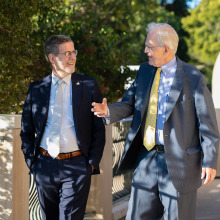 Two men in suits walking side-by-side and engaging in a conversation