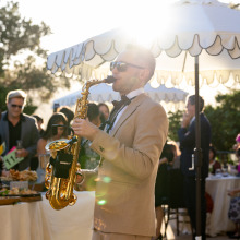 A musician in a tan suit playing a golden saxophone