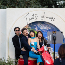 Four guests posing playfully on a red Vespa scooter prop