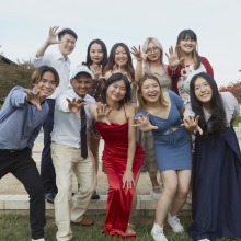 A group of ten students smile and hold their hands in a claw-like pose during the Welcome Reception