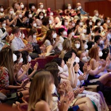 A large gathering of masked students applaud as they are seated in the Performing Arts Center