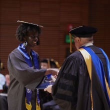 A graduate shakes hands with President Feasel as they accept their diploma