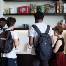 Students wearing backpacks peruse a bookshelf with various magazines in the new Global Language and Culture Center