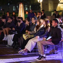 Students listen to a speaker during the candlelit vigil for Daisaku Ikeda