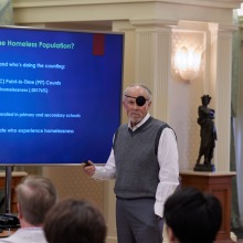 A man speaks using a screen as a visual aid during the symposium