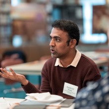 A conference attendee gestures with his hand as he speaks during a small group discussion.