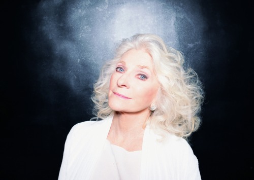 Judy Collins dressed in white against a blue background