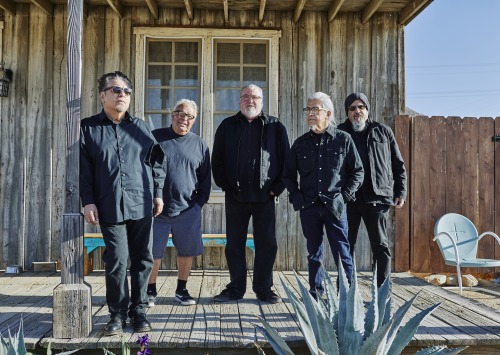 Los Lobos band against a gray western building