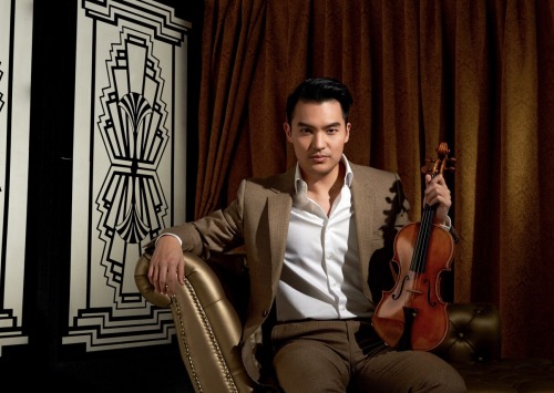 Man in brown suit sitting in chair holding a violin