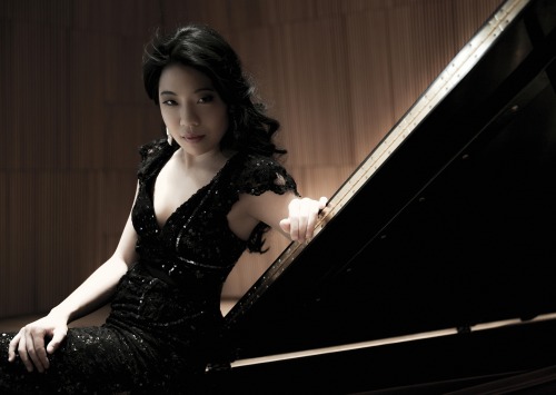 Joyce Yang in black dress sitting at piano