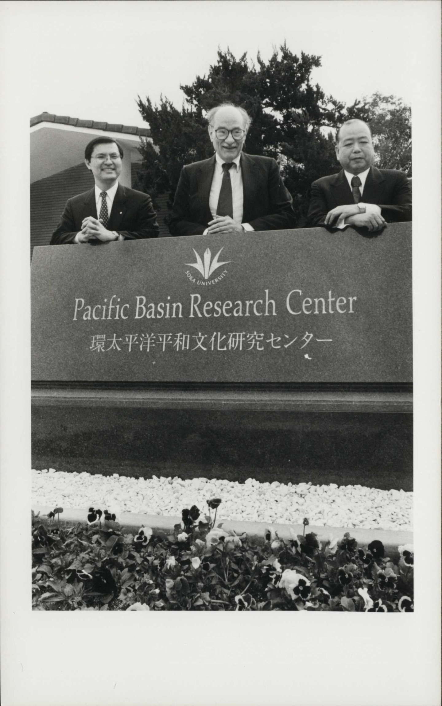 Three men stand behind the PBRC sign to commemorate its opening.