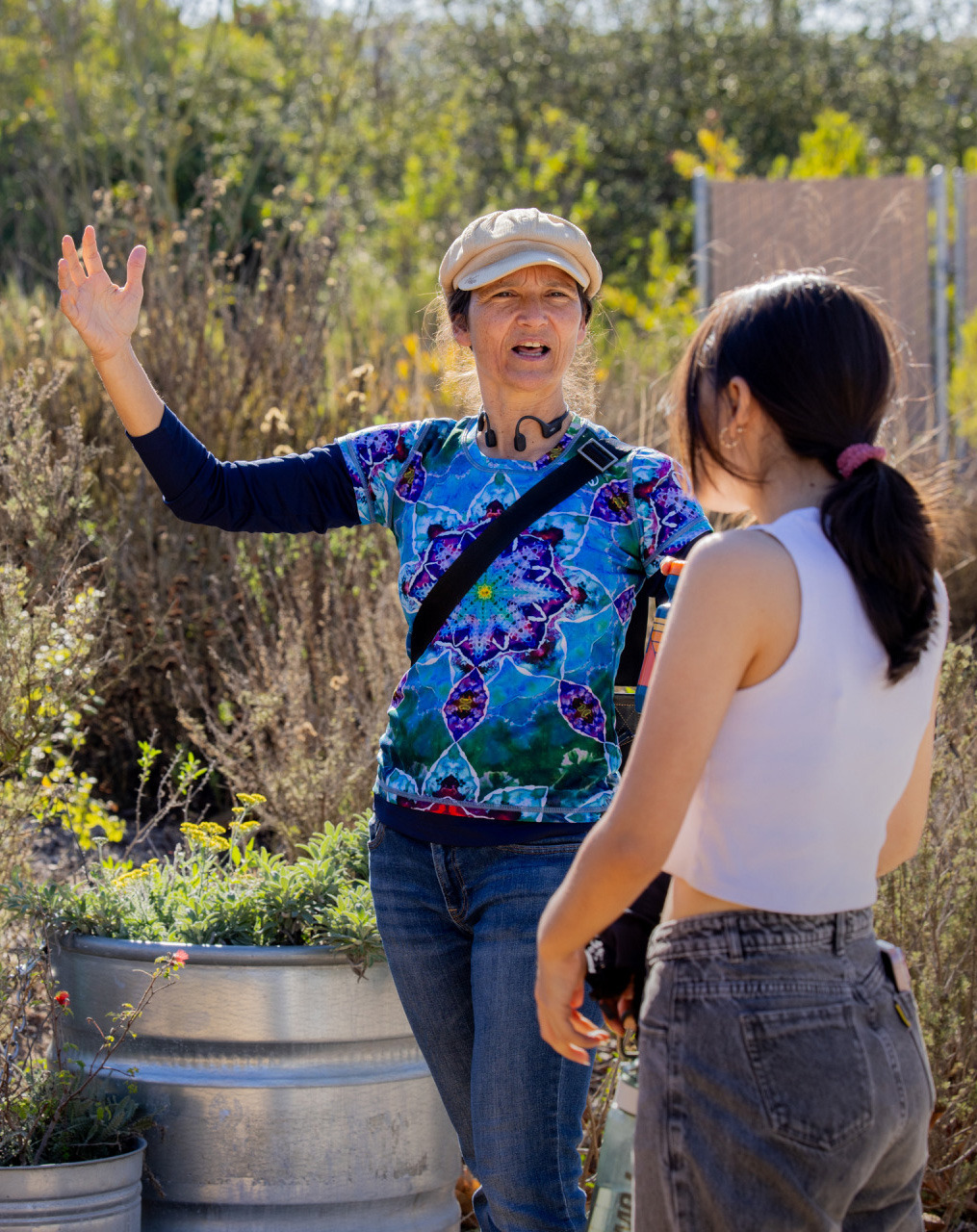 Soka University Professor Dr. Deike Peters gestures while speaking to a student during a field trip at Ballona Discovery Park, standing next to an educational park map sign.