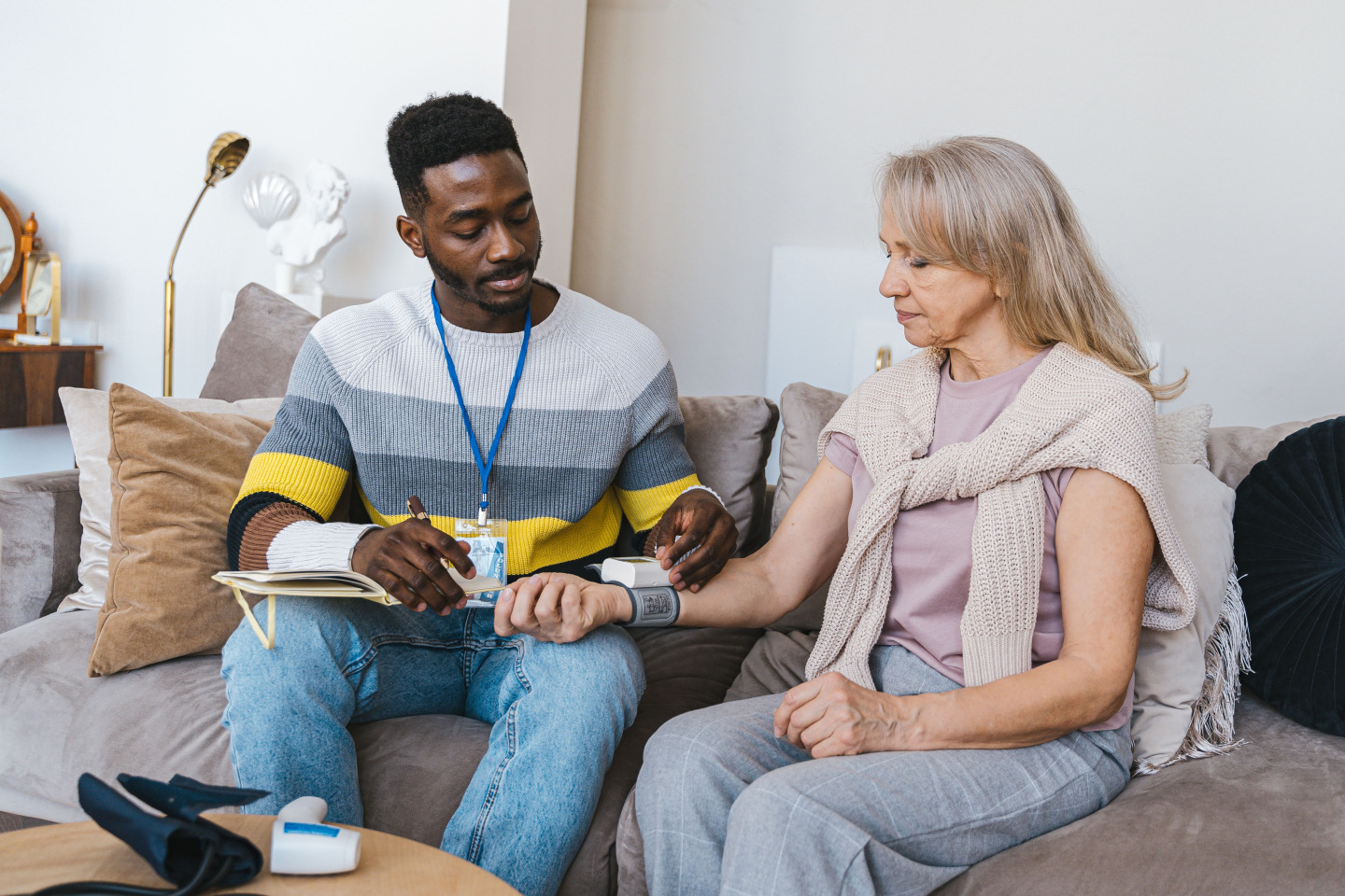 Volunteer checking elderly woman's blood pressure at home