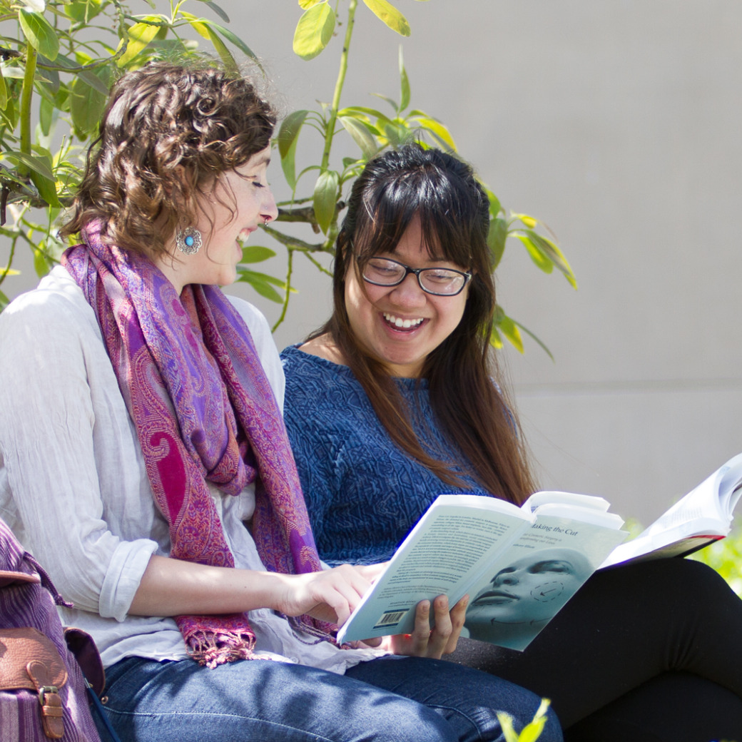 Students smiling and sharing a book