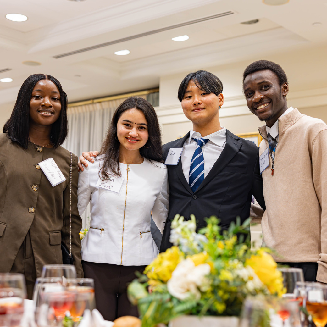 Four formally dressed students pose during an etiquette training event.