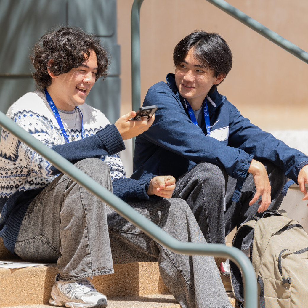 Two students sit on a staircase and chat.