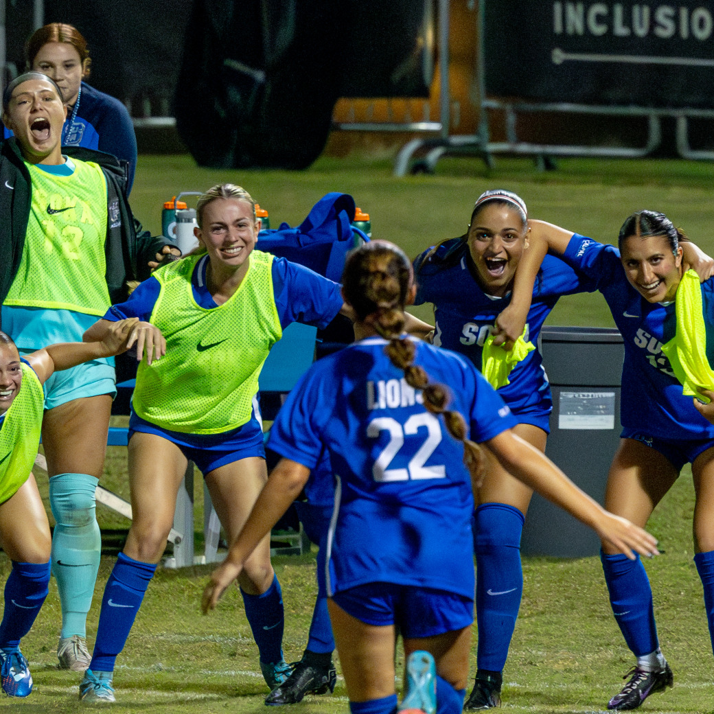 Women's soccer players rush together to celebrate