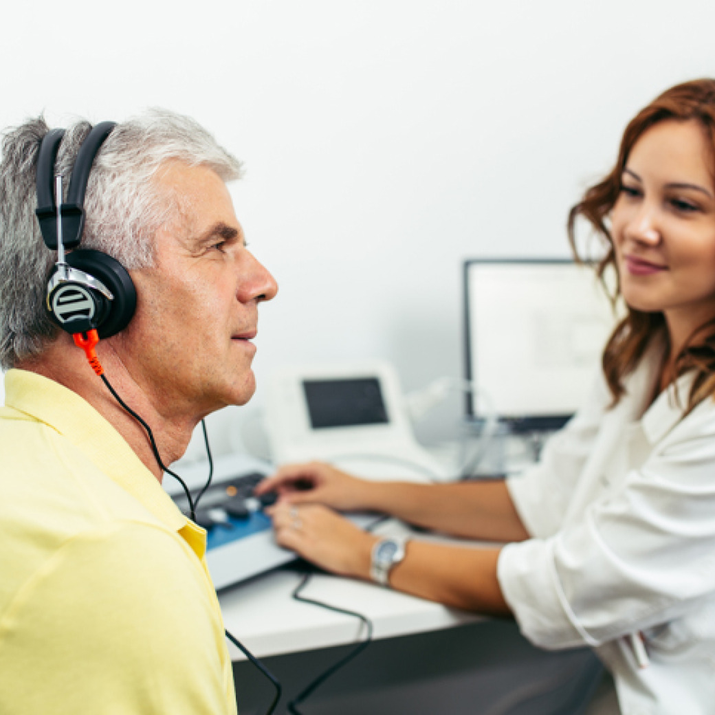 An audiologist evaluating an old man's hearing
