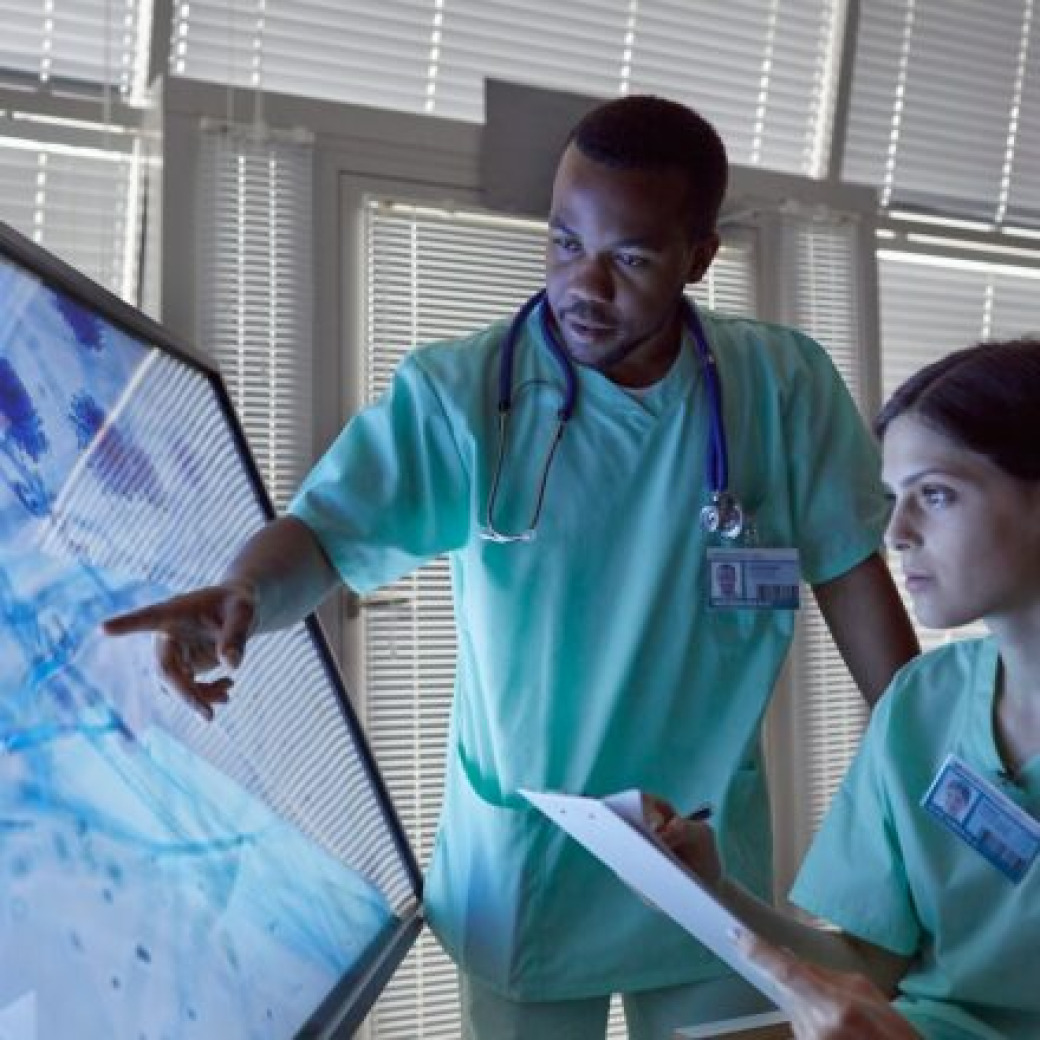 PAs examining digital data on a large interactive display screen in a modern healthcare or laboratory setting