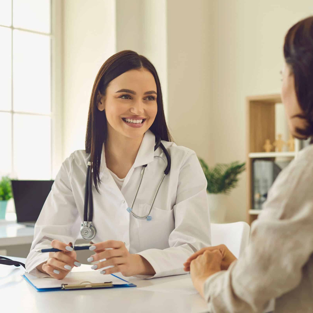 physician smiling and talking to patient on clinic desk