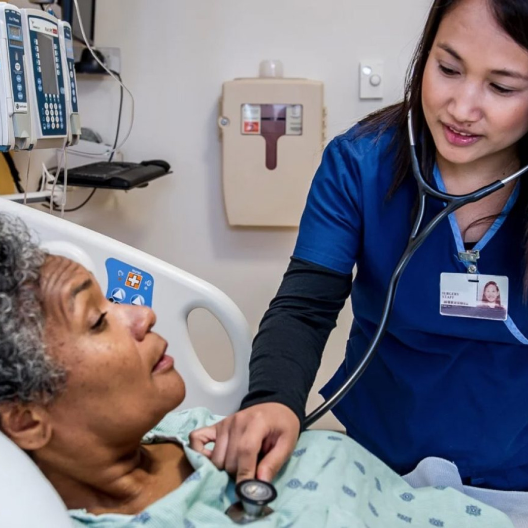A nurse doing regular check for an elder patient on the hospital bed